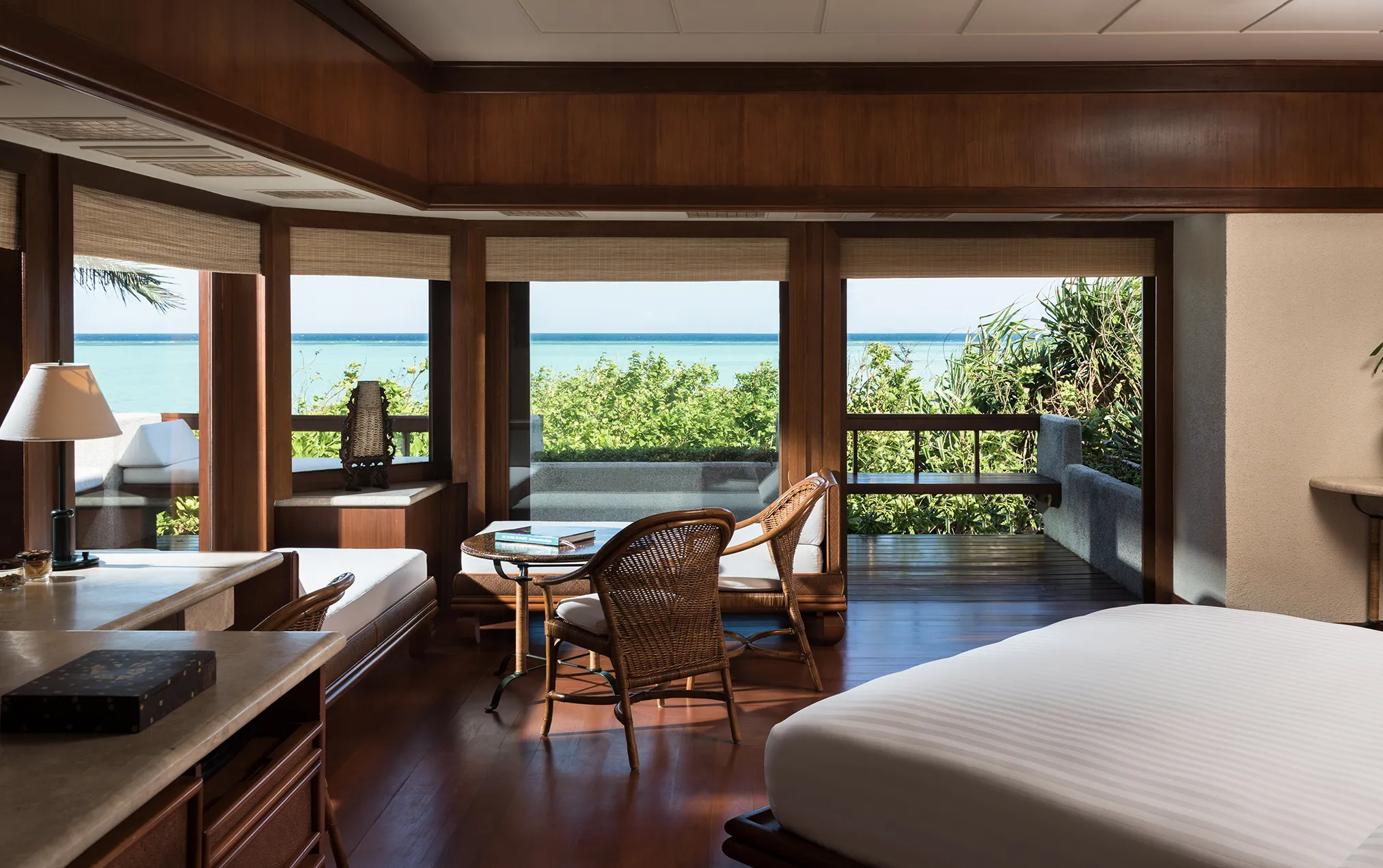 A beachfront casita at Amanpulo with a wide wooden deck opening directly onto white sand and the sea