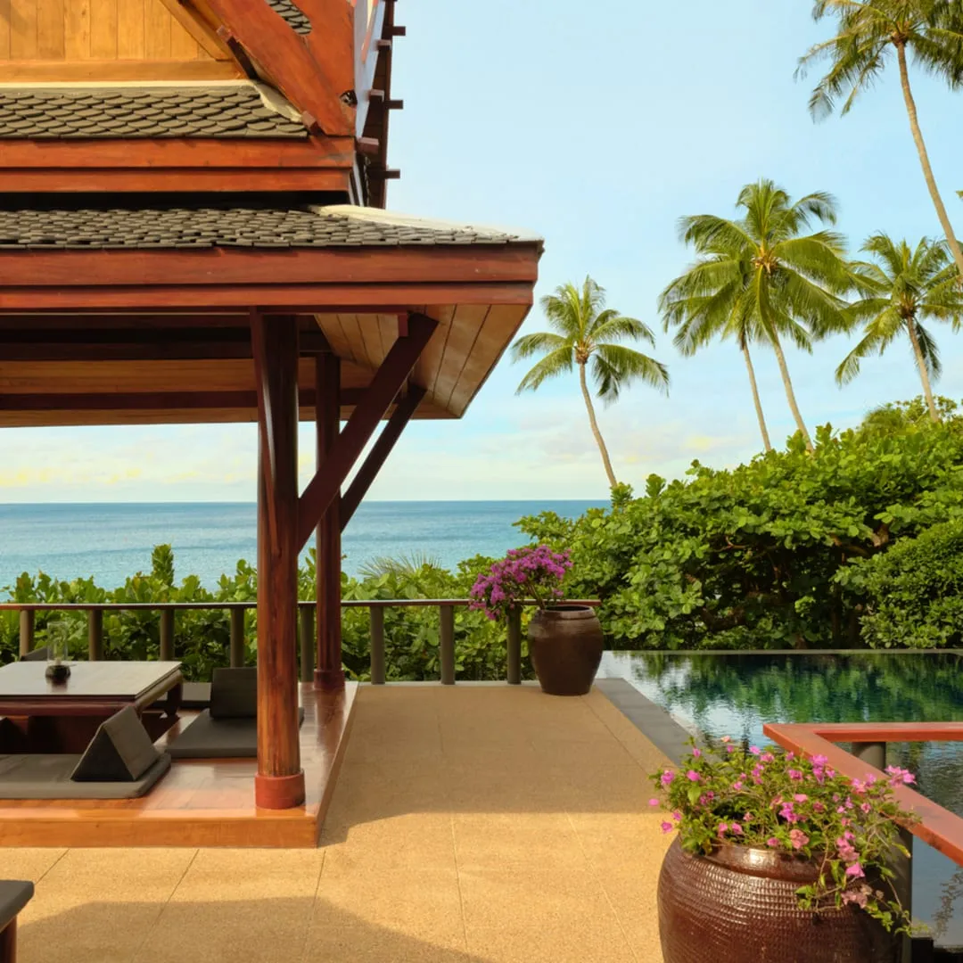 A wood-panelled guest pavilion at Amanpuri set among coconut palms with a pitched, tiled roof