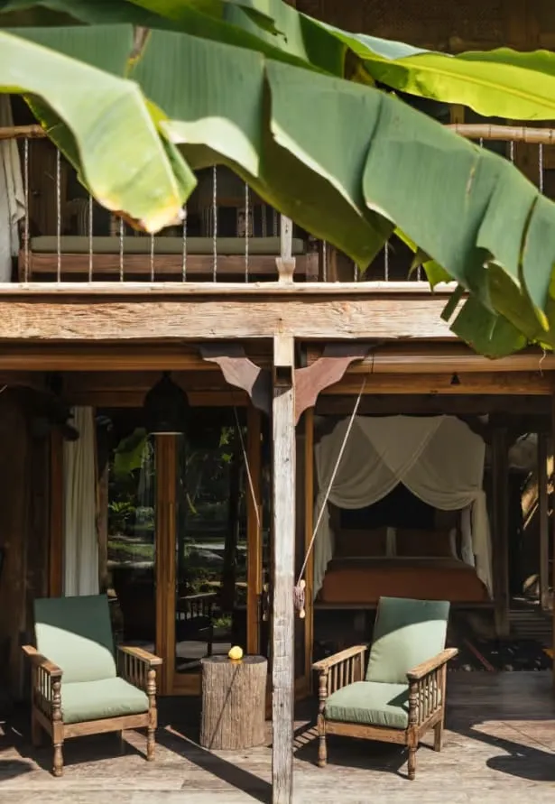 Restored antique Javanese bridal house with carved teak columns and open-air veranda at Bambu Indah