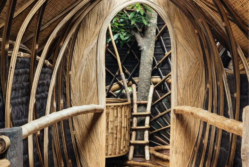 Curved bamboo roof structure with hand-hammered copper shingles above an open-air riverside dining room