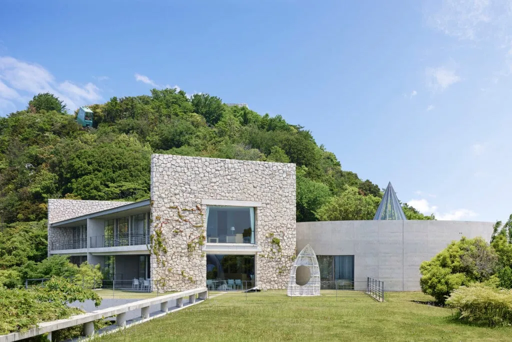 A guest room inside Benesse House Museum with a contemporary artwork on the wall and a balcony overlooking the sea