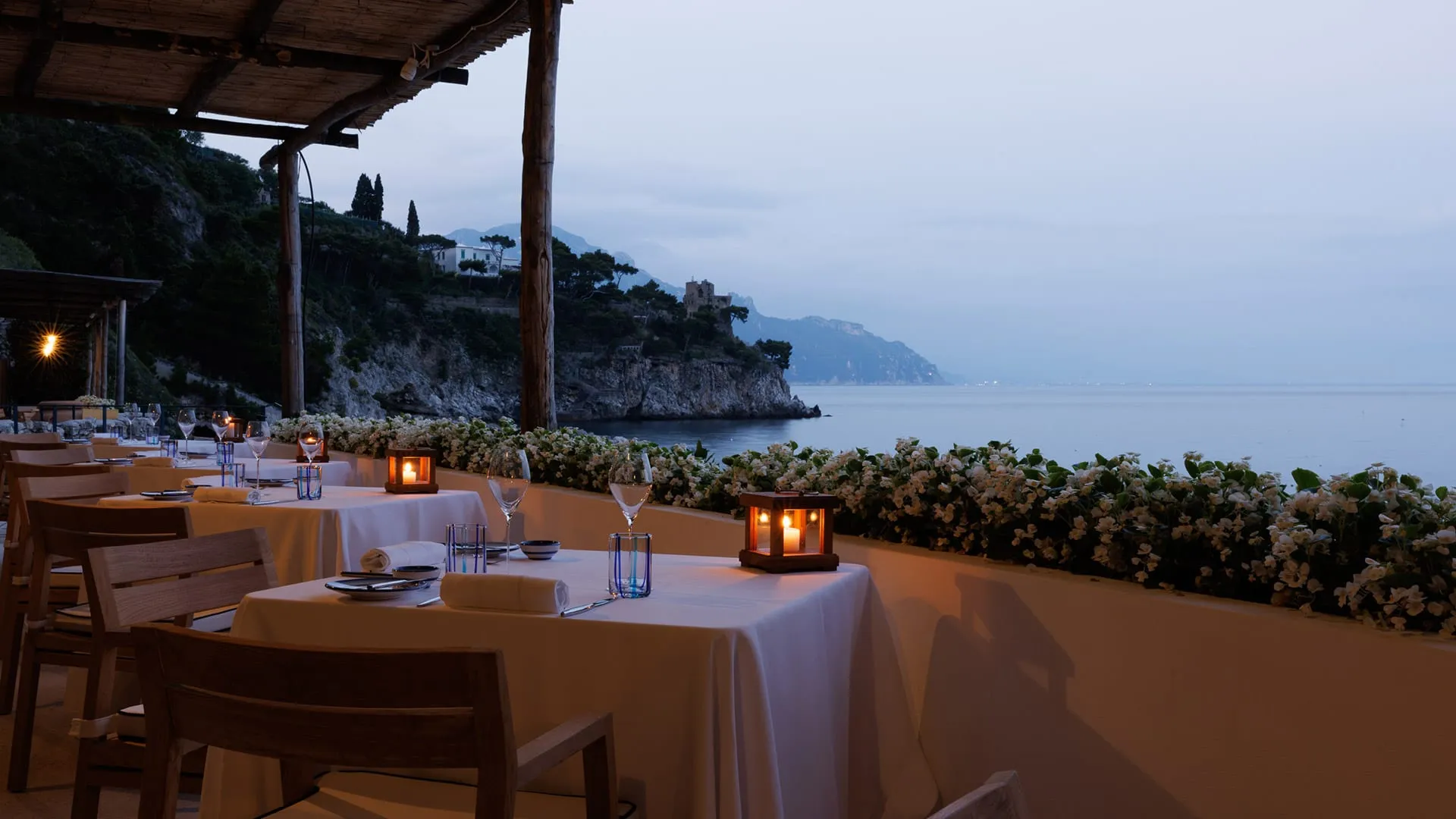 A restaurant terrace set for dinner above the Mediterranean at Borgo Santandrea