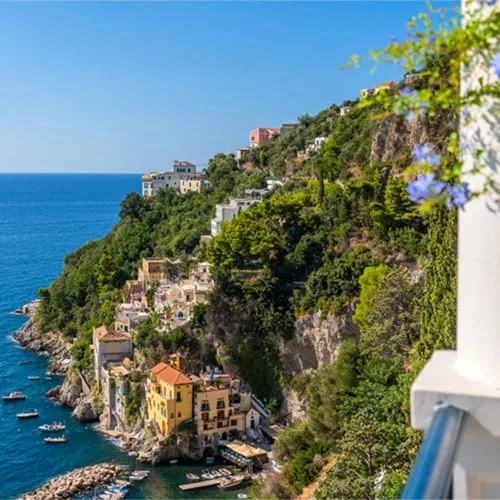 Borgo Santandrea's terraced cliffside hotel cascading down the rock face above the Amalfi Coast, with the sea and private beach below