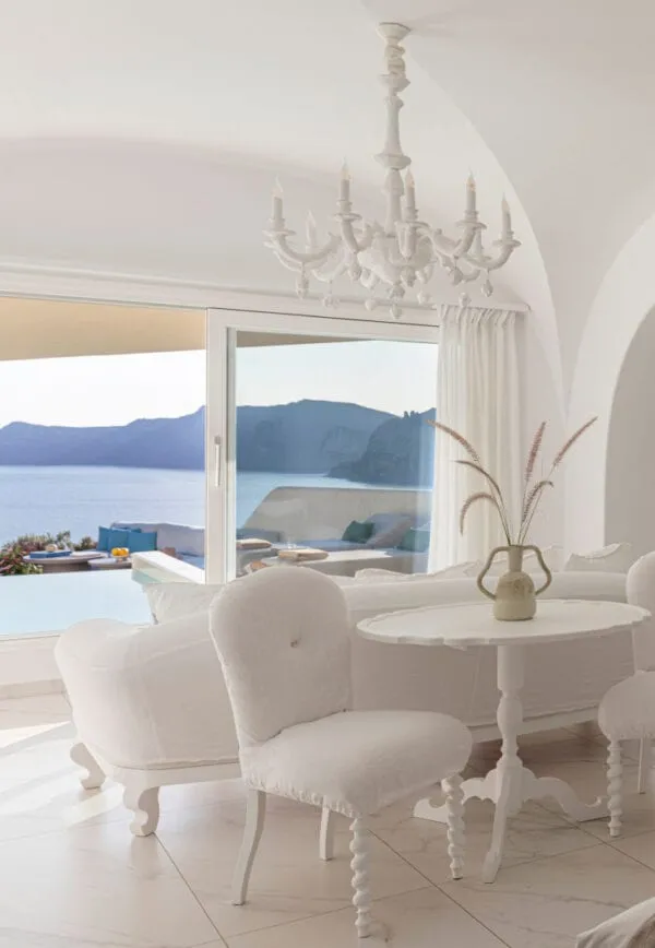 Whitewashed cubic suite volumes at Canaves Oia Suites set into the sloping caldera cliff