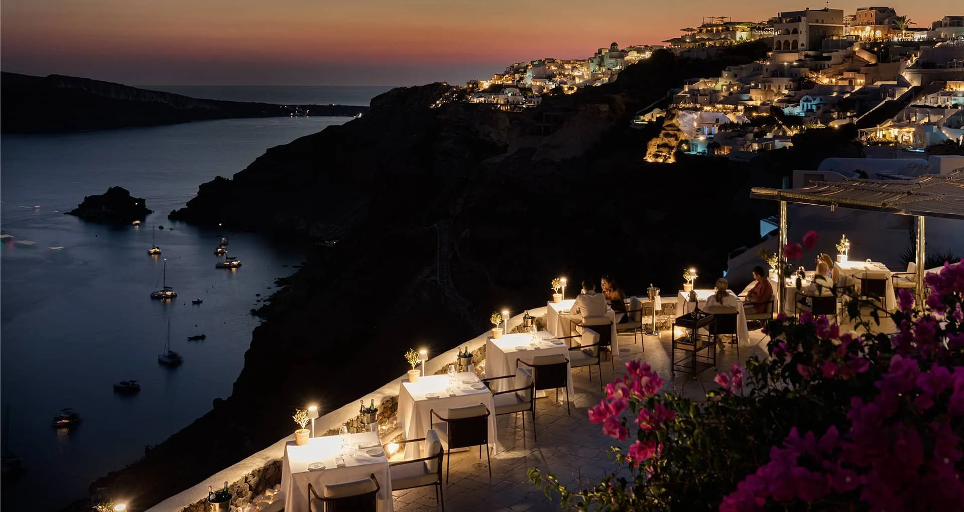 Candlelit table setting at Petra Restaurant at Canaves Oia Suites at sunset