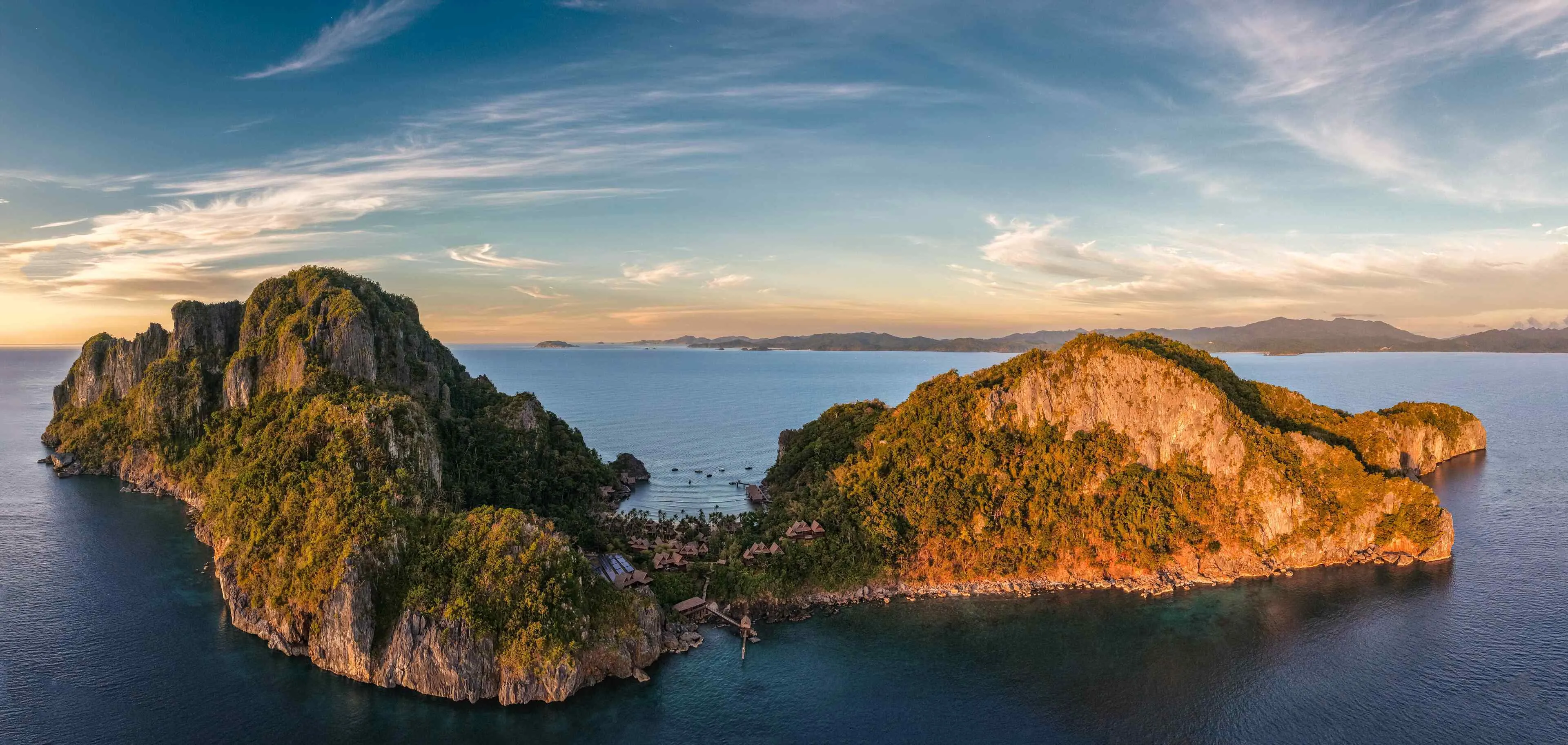 A private beach dining setup at Cauayan Island Resort at sunset with limestone islands in the distance