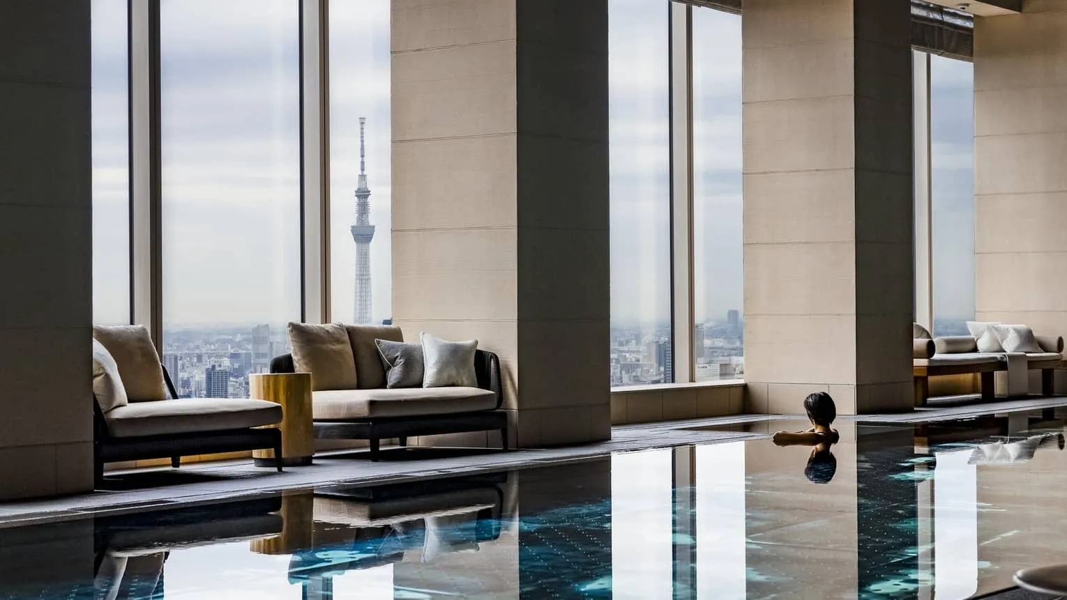 The 20-metre indoor pool at The Spa, framed by floor-to-ceiling windows with panoramic Tokyo skyline views