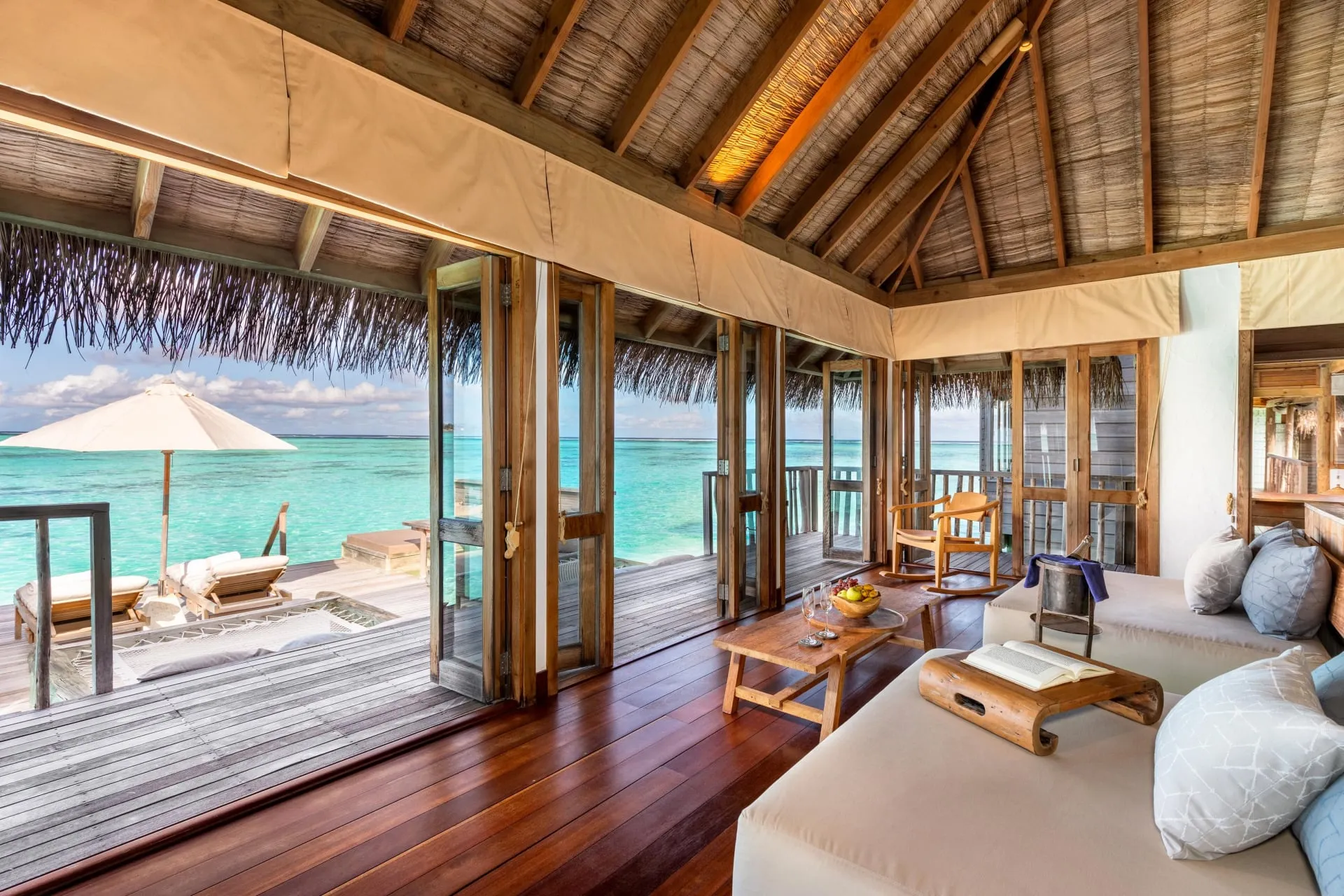 Timber walkway connecting overwater villas above a shallow turquoise lagoon at Gili Lankanfushi