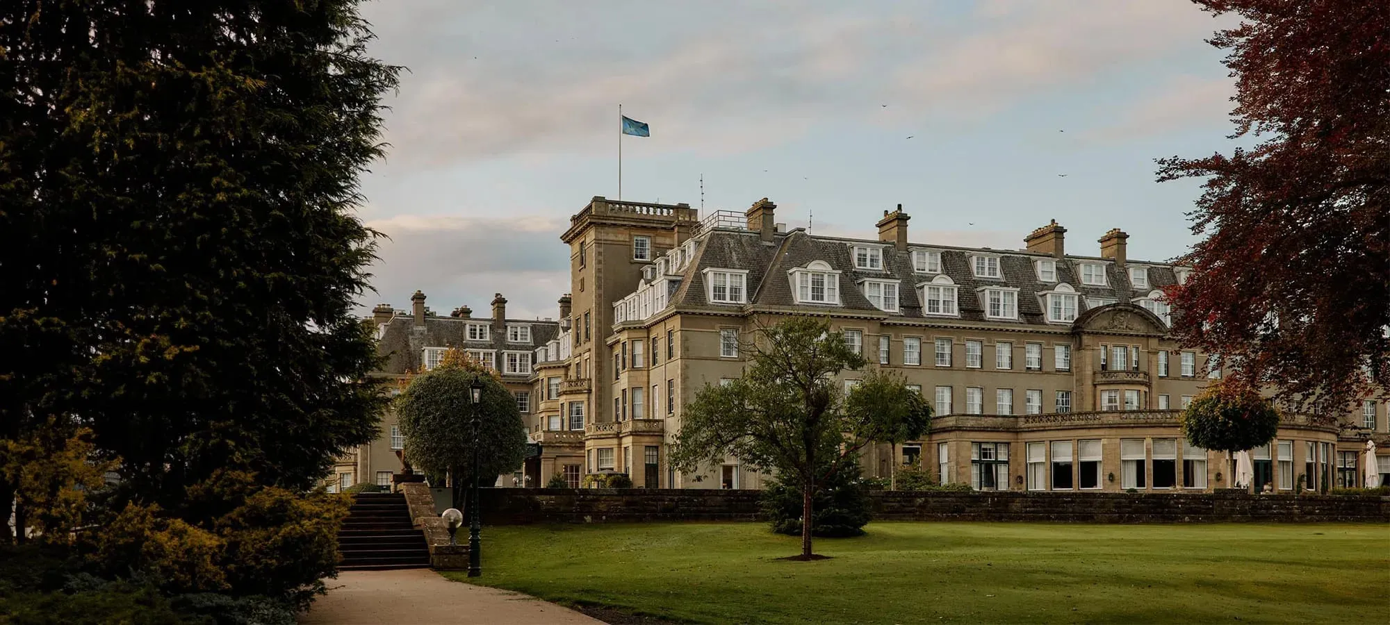 The grand sandstone facade of Gleneagles Hotel rising above its Perthshire parkland at dusk
