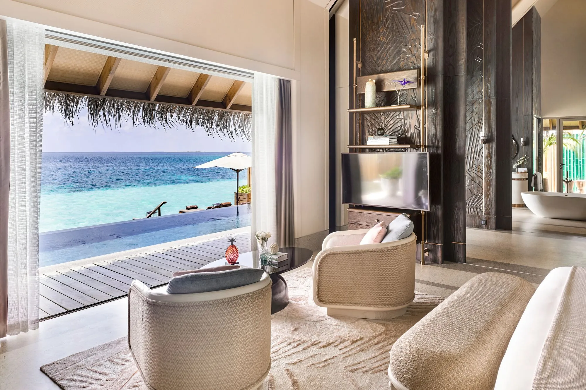 Overwater villas at JOALI Maldives connected by a long timber boardwalk over a turquoise lagoon in Raa Atoll
