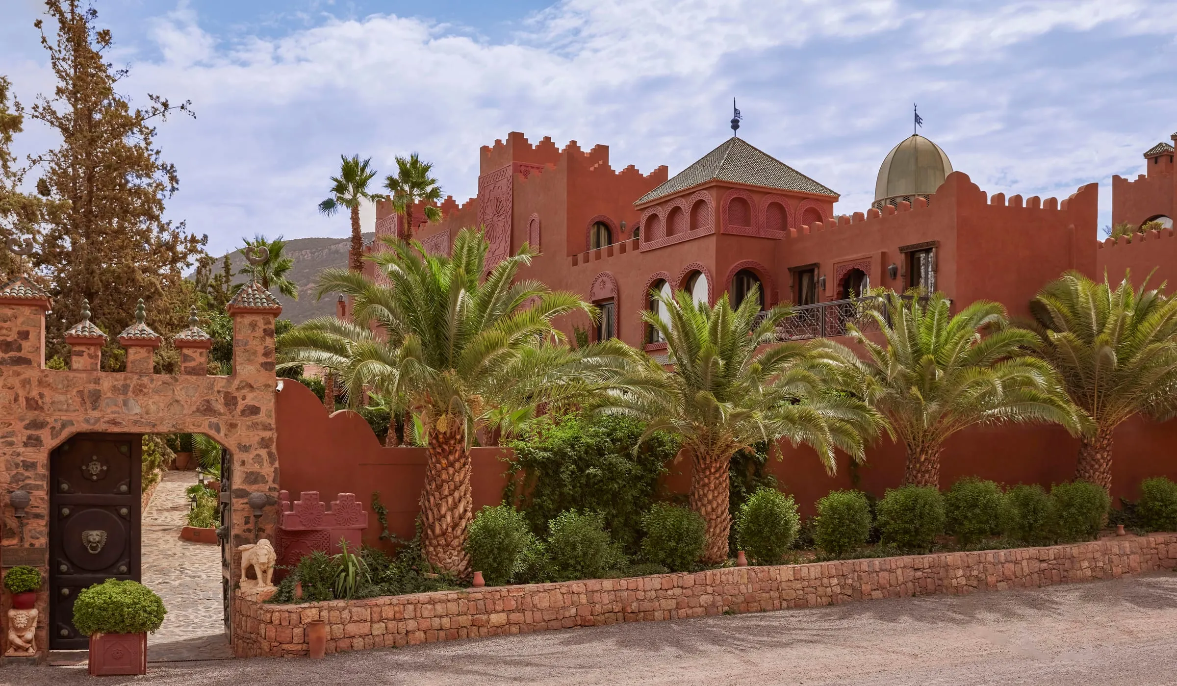 Kasbah Tamadot's tiled courtyards and tower rising above the Asni Valley with the High Atlas Mountains behind