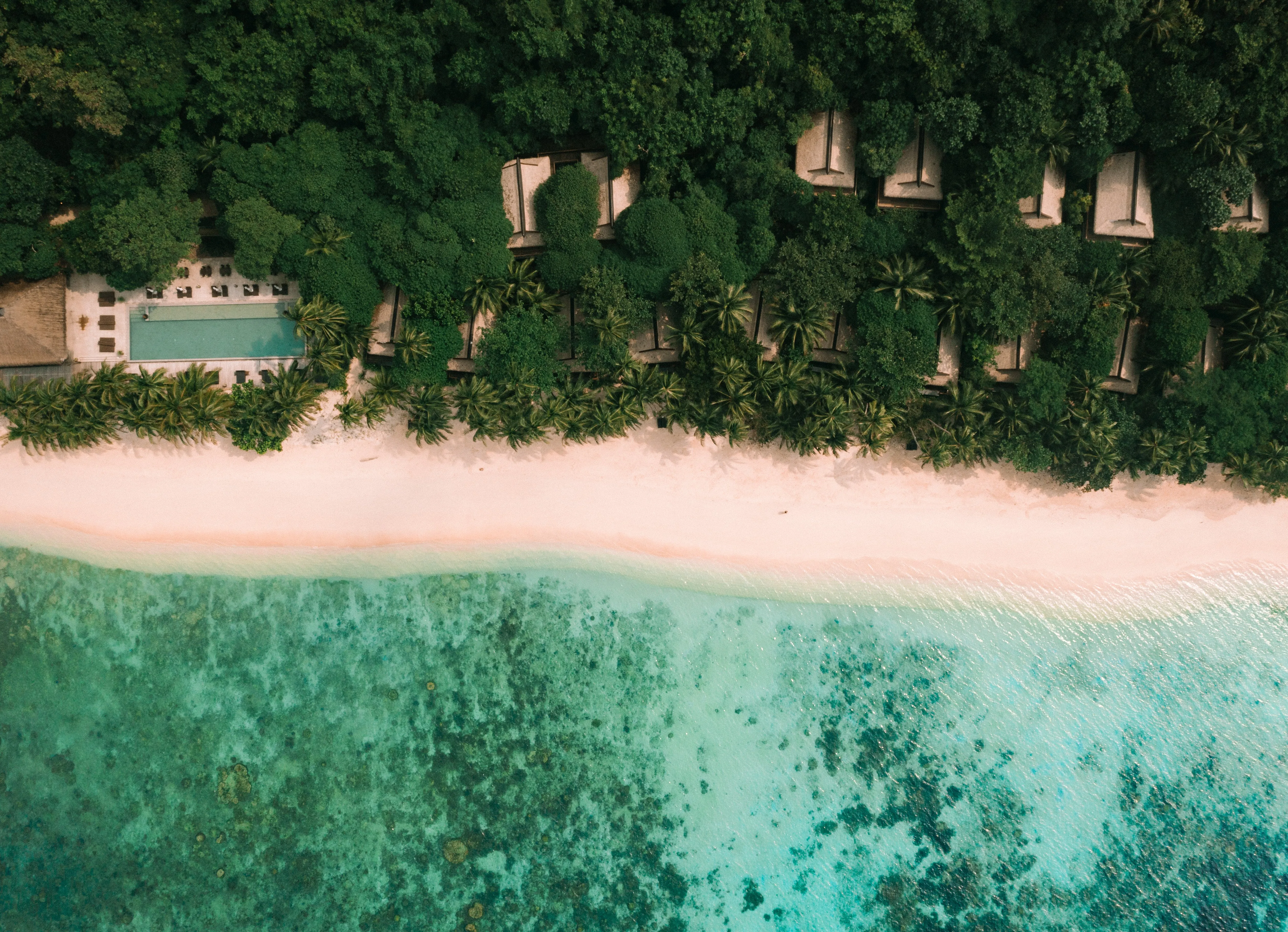 A thatched-roof villa on stilts above the forest canopy at Pangulasian Island Resort, with Bacuit Bay's limestone karst islands visible in the distance