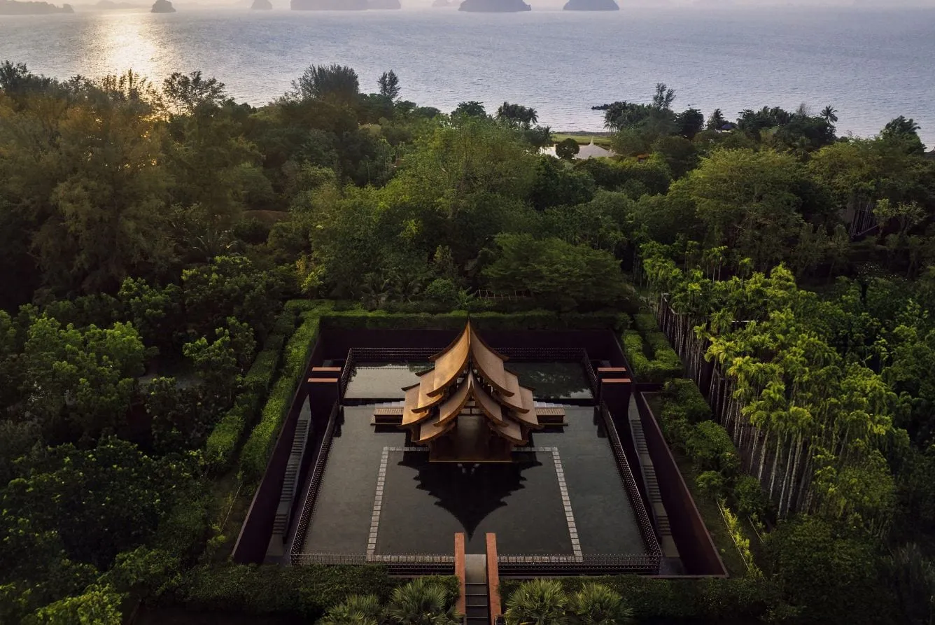 A pitched-roof Thai pavilion at Phulay Bay, A Ritz-Carlton Reserve, set over a still reflection pool with Krabi's limestone karsts beyond
