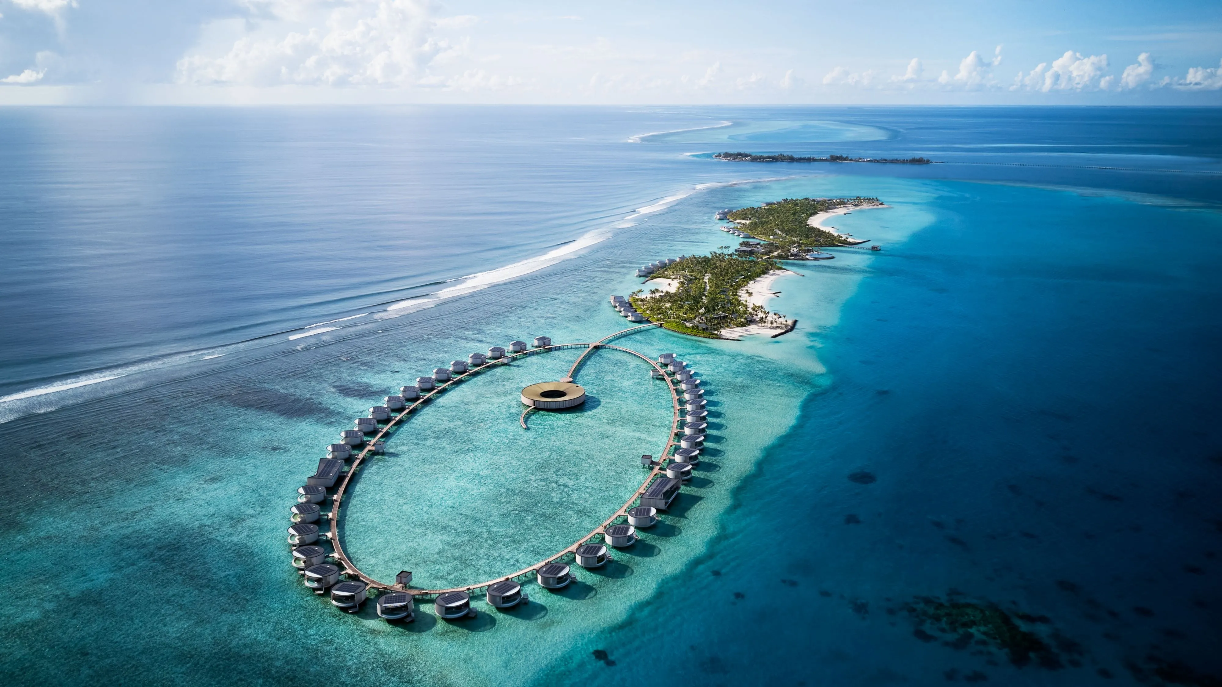 A circular overwater villa at The Ritz-Carlton Maldives, Fari Islands, its curved timber-slatted facade set against a turquoise lagoon