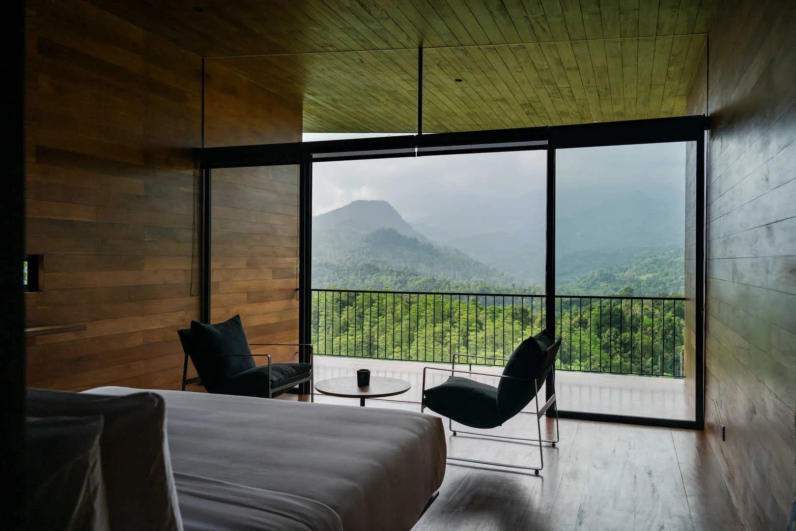 Glass-walled chalet interior with polished concrete floors overlooking forest canopy