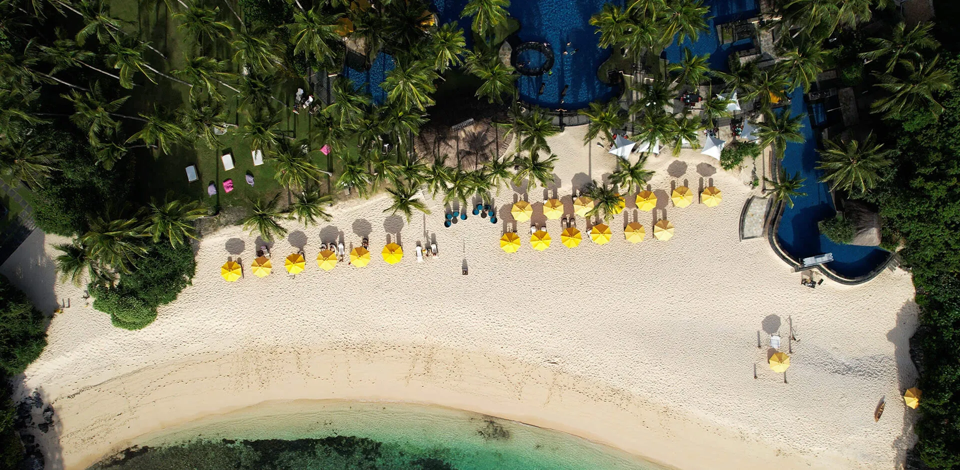 Aerial view of Shangri-La Boracay Resort & Spa's beachfront pool and gardens meeting the forested hillside above Punta Bunga cove