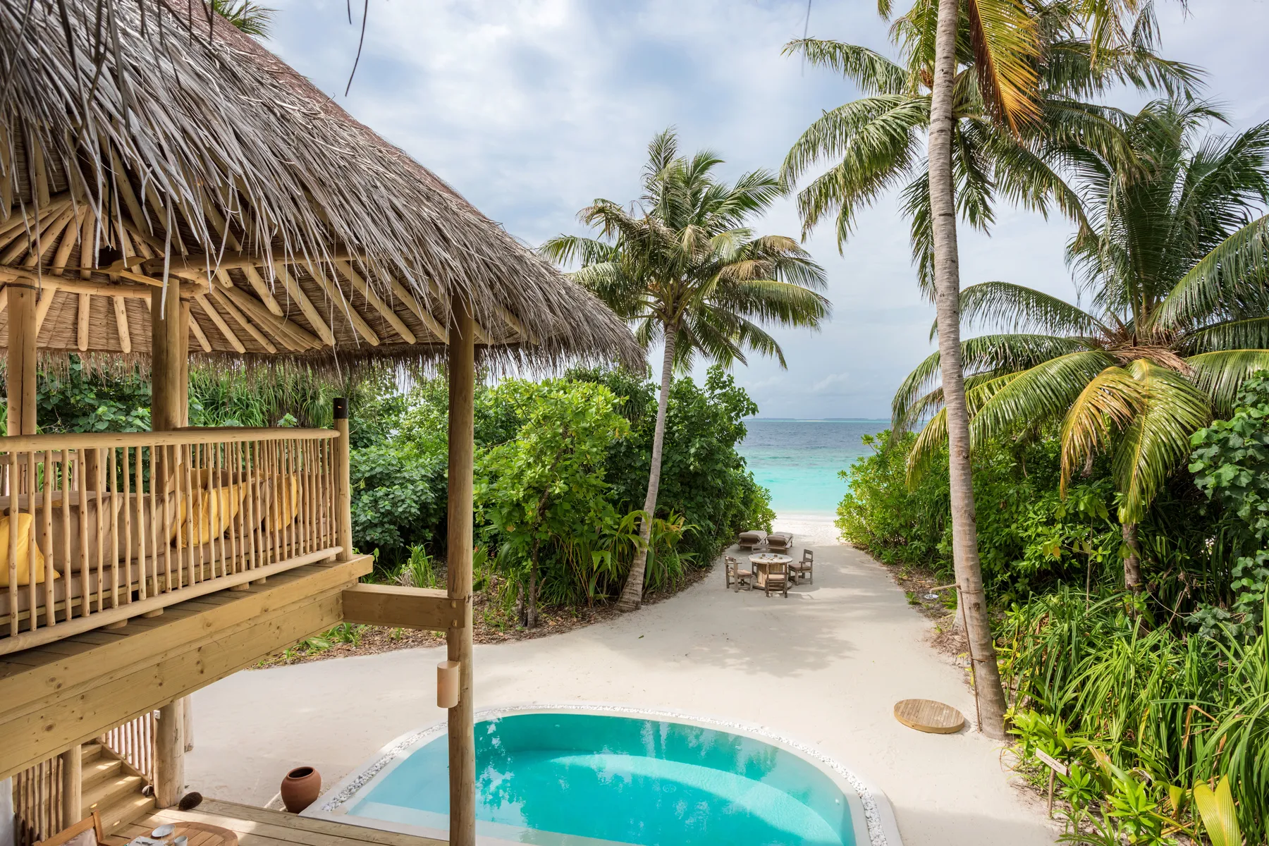 Sandy jungle pathway winding between trees toward guest villas at Soneva Fushi