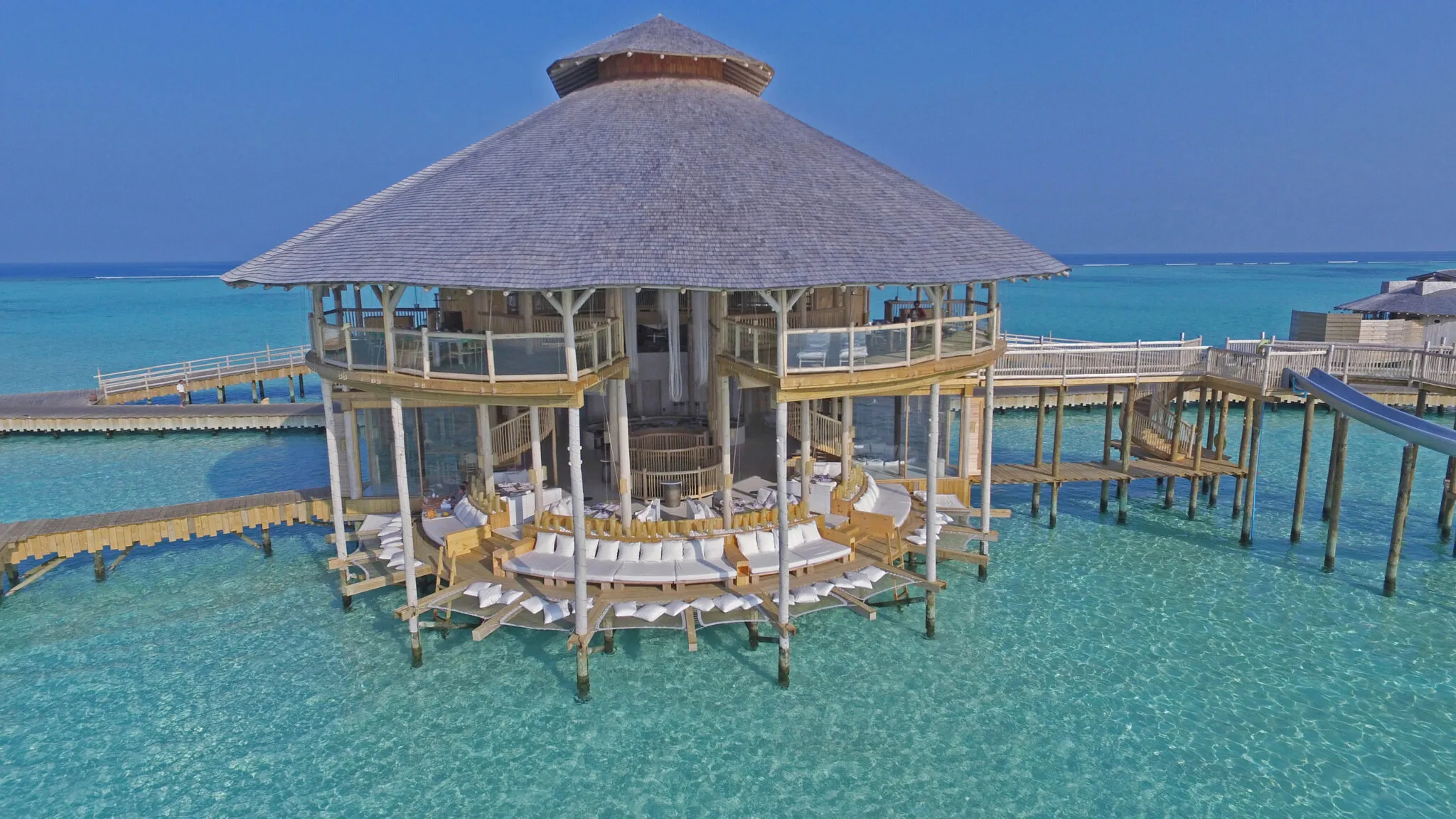 A curved waterslide descending from an upper deck into the lagoon at Soneva Jani