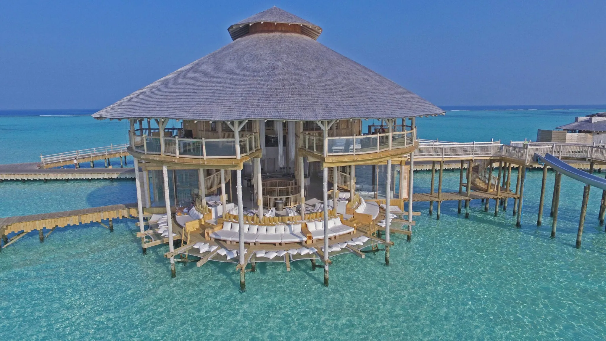 A curved waterslide descending from an upper deck into the lagoon at Soneva Jani
