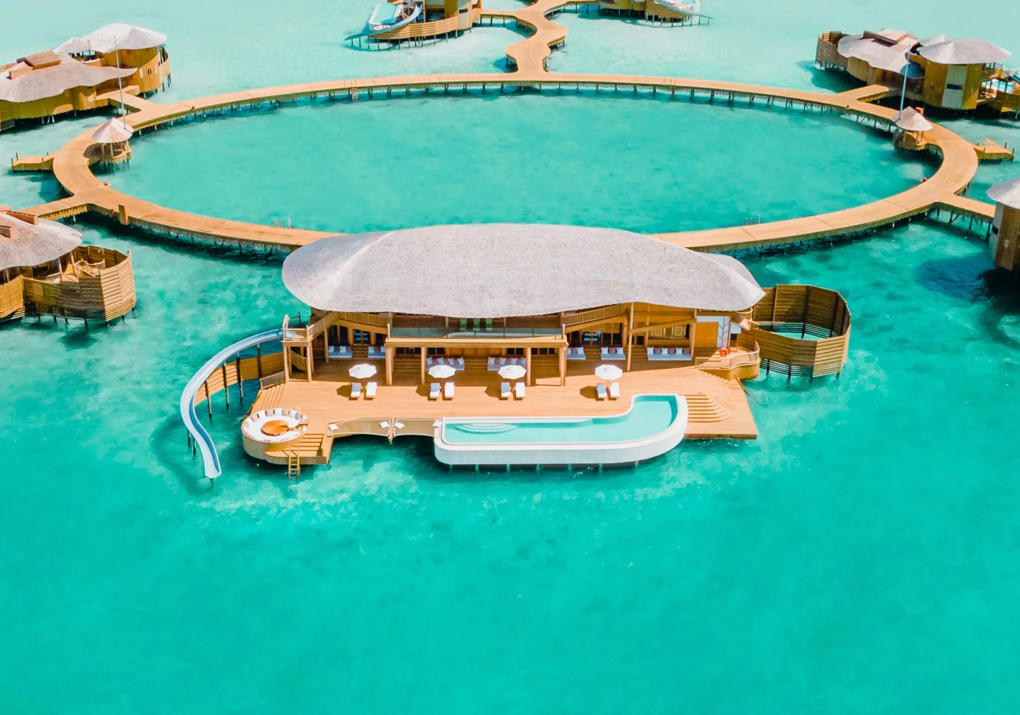 Overwater villas with retractable roofs strung along a wooden jetty across the lagoon at Soneva Jani in Noonu Atoll, Maldives