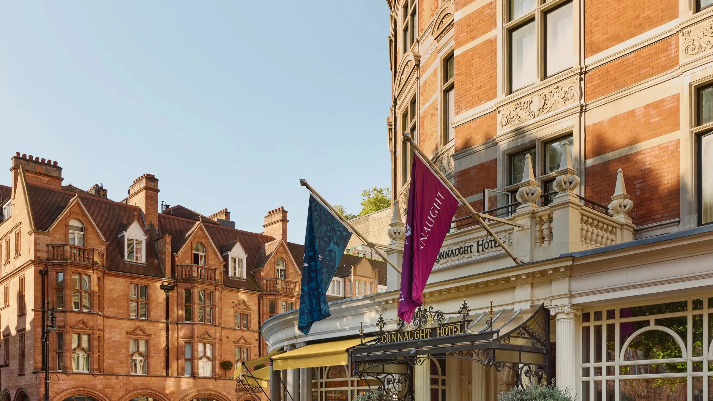 The Connaught's Carlos Place facade at dusk, its awnings lit and doormen stationed beneath the hotel's Mayfair entrance