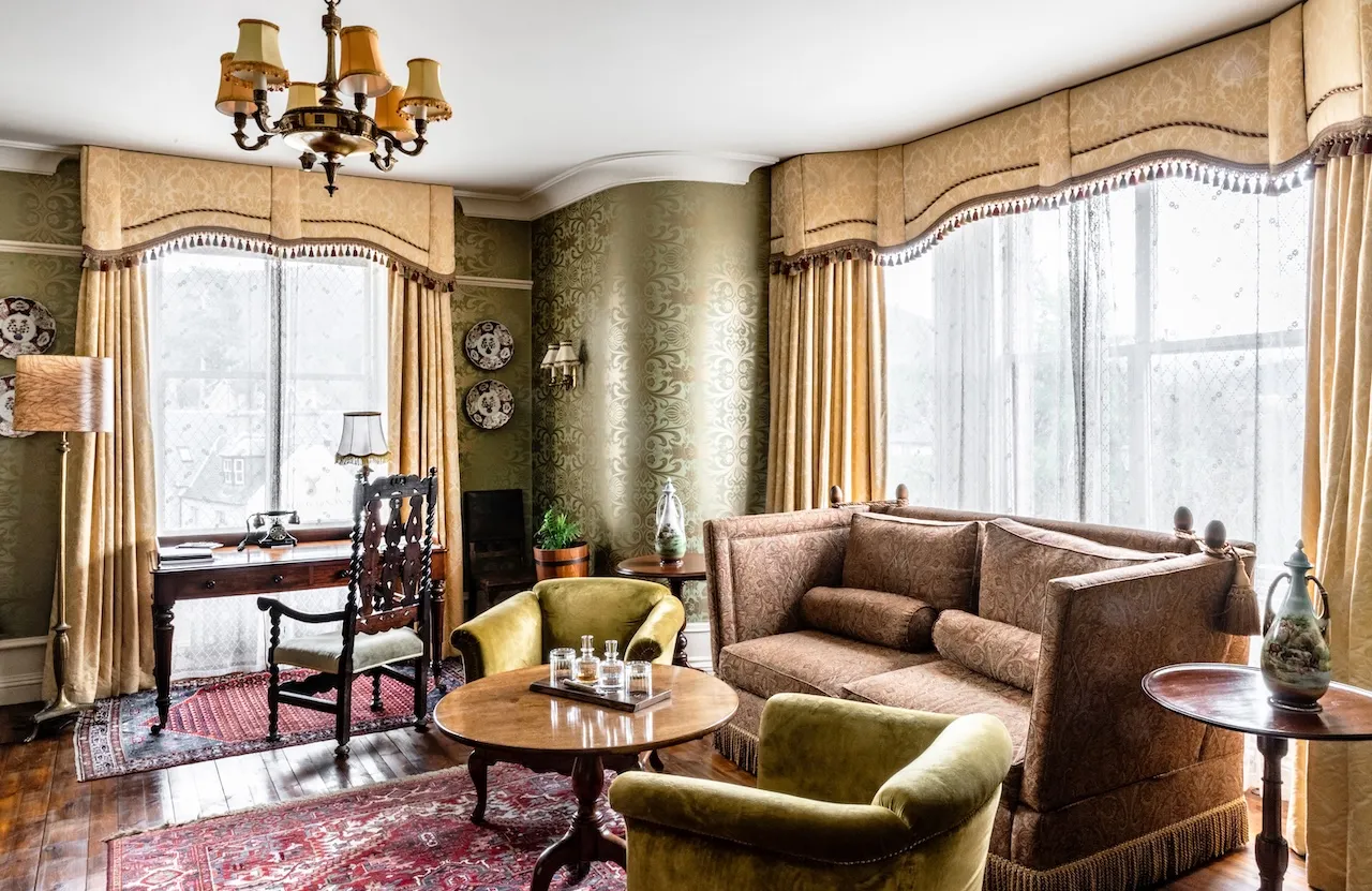 A maximalist guest room at The Fife Arms with hand-painted headboard, antique furniture and layered textiles