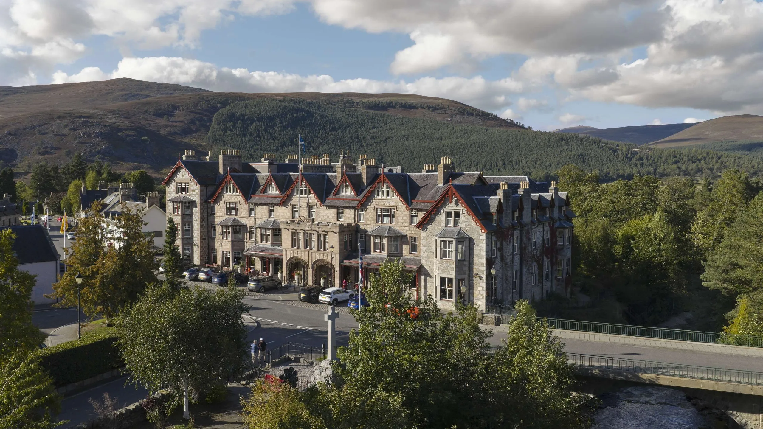 The pink harled Victorian facade of The Fife Arms hotel on Mar Road in Braemar, with the Cairngorms rising behind it