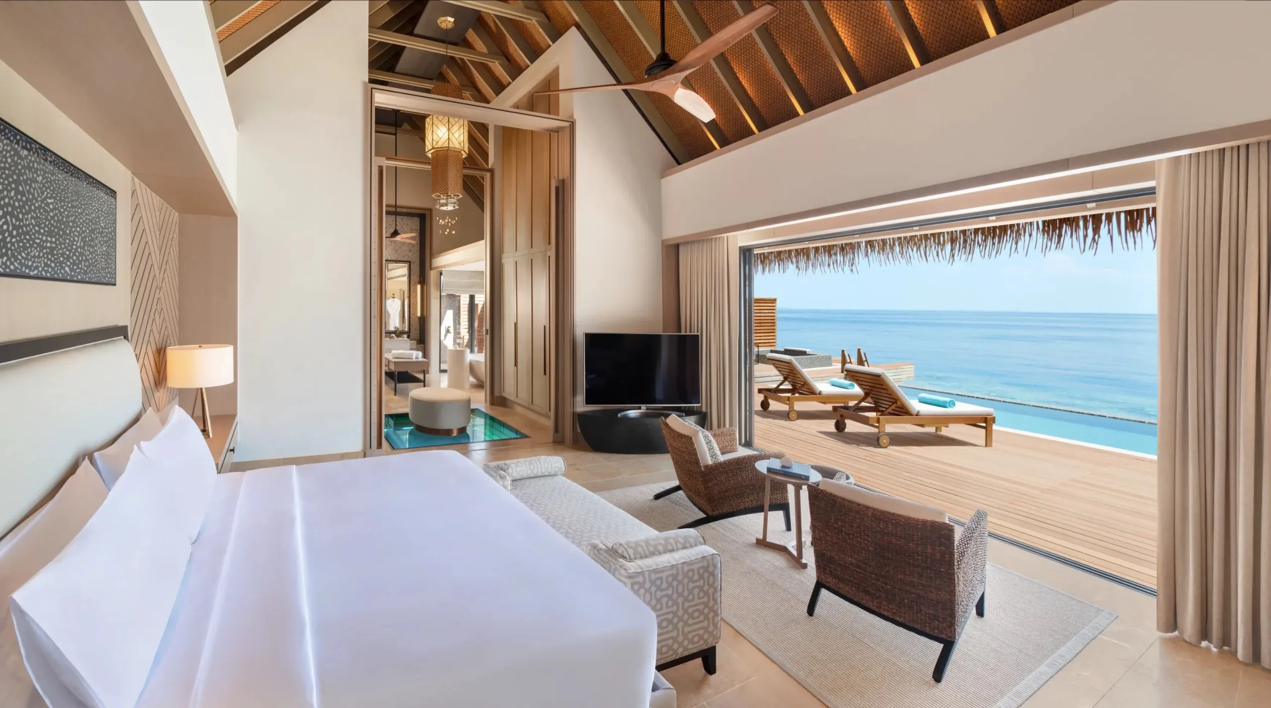 A private infinity pool on the deck of an overwater villa looking out across the lagoon toward the horizon